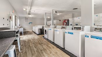 A laundry room with washers and dryers lined up